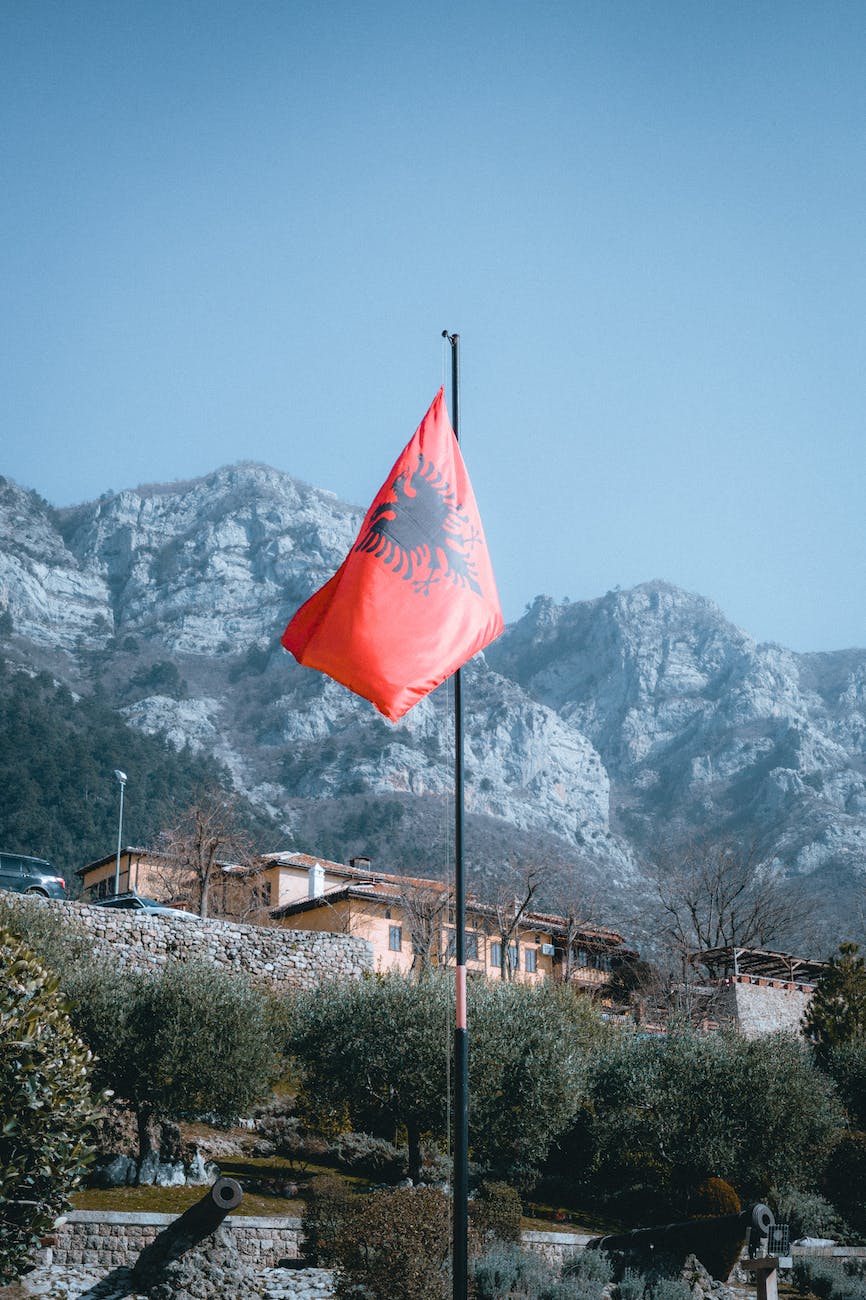 rocky mountains and an albanian flag in foreground