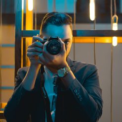 man in black suit holding canon dslr camera