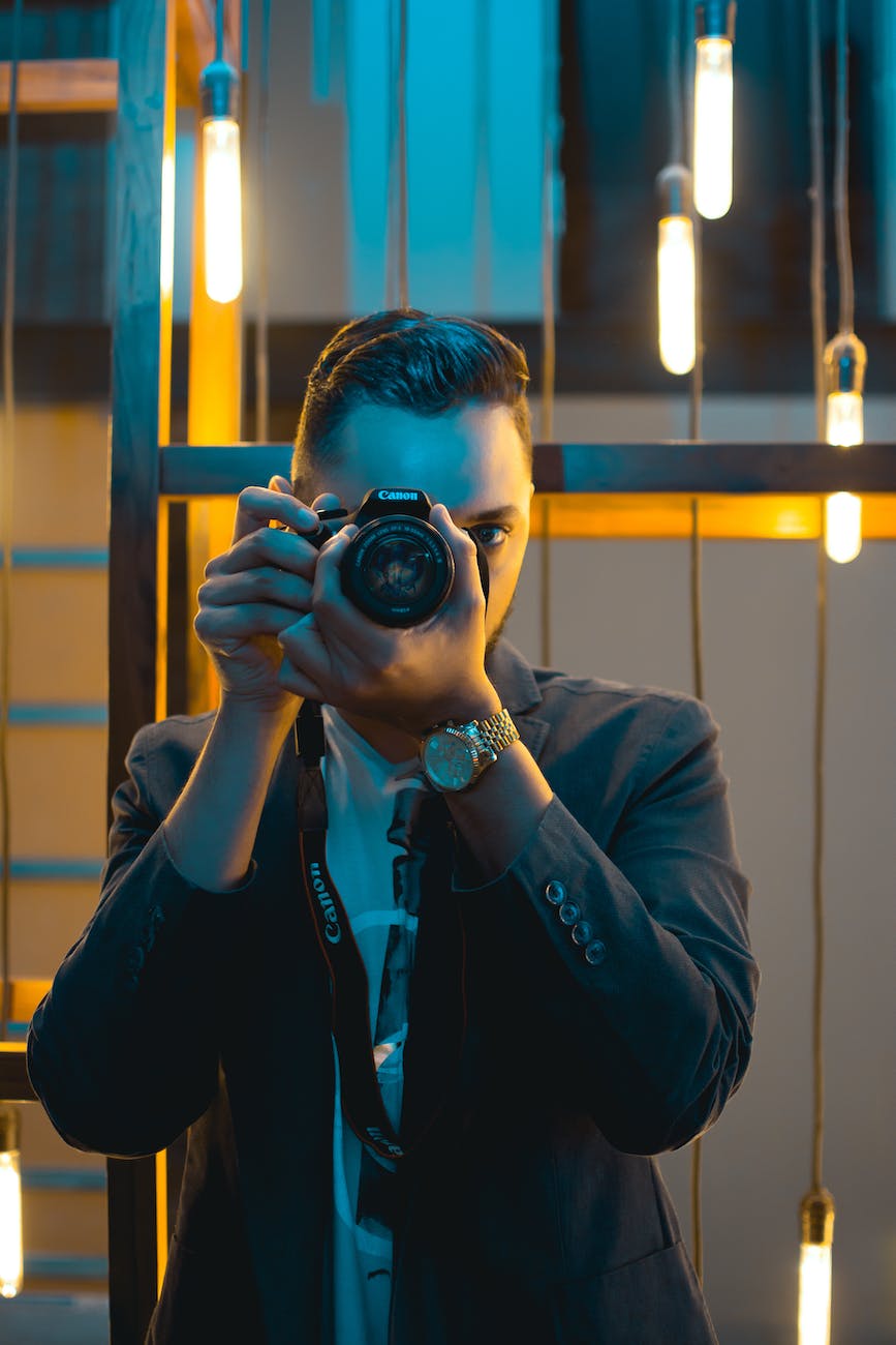 man in black suit holding canon dslr camera