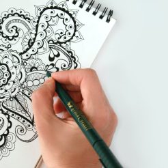 person holding black pen sketching flower