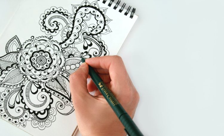 person holding black pen sketching flower