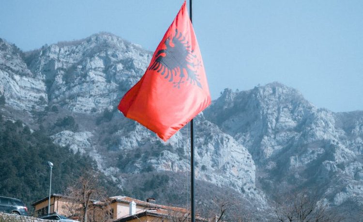 rocky mountains and an albanian flag in foreground