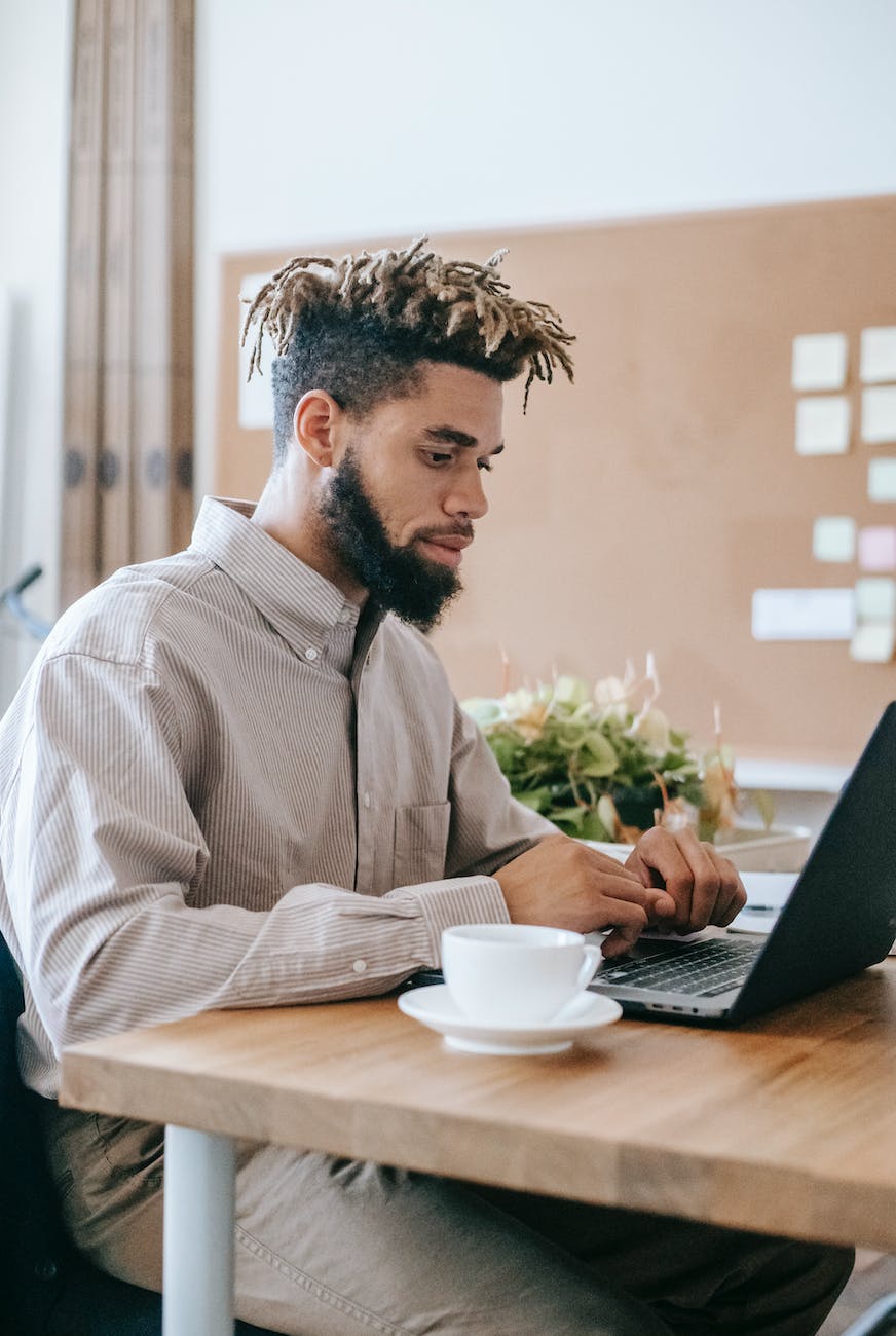 man in dress shirt sitting at the table using laptop computer