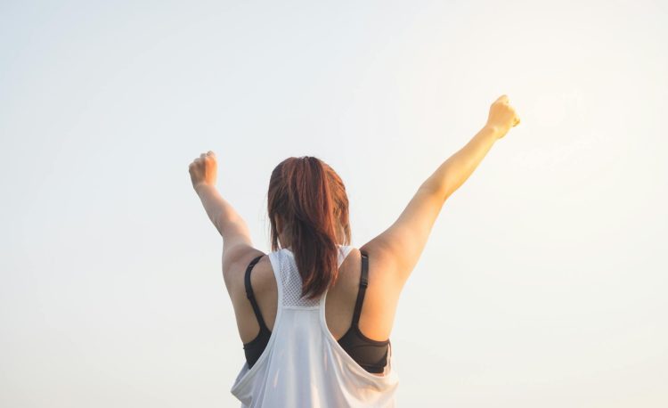 woman wearing black bra and white tank top raising both hands on top