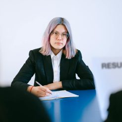 woman sitting by a table taking notes at a meeting