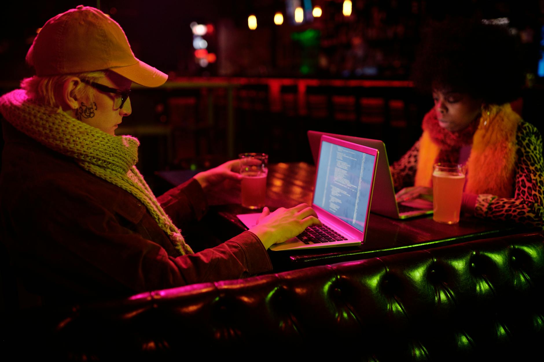 a man and a woman using their laptop in a bar