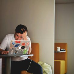 man in white shirt using macbook pro