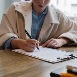 focused woman writing in clipboard while hiring candidate