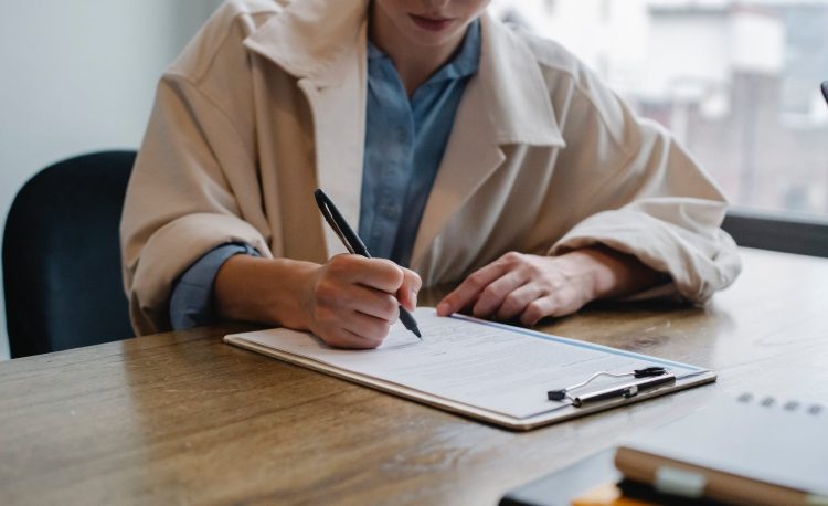 focused woman writing in clipboard while hiring candidate