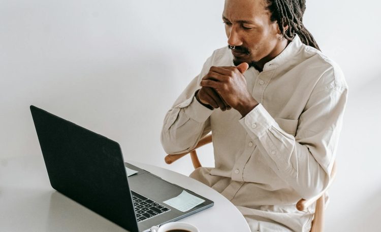 serious black man working on laptop in light room
