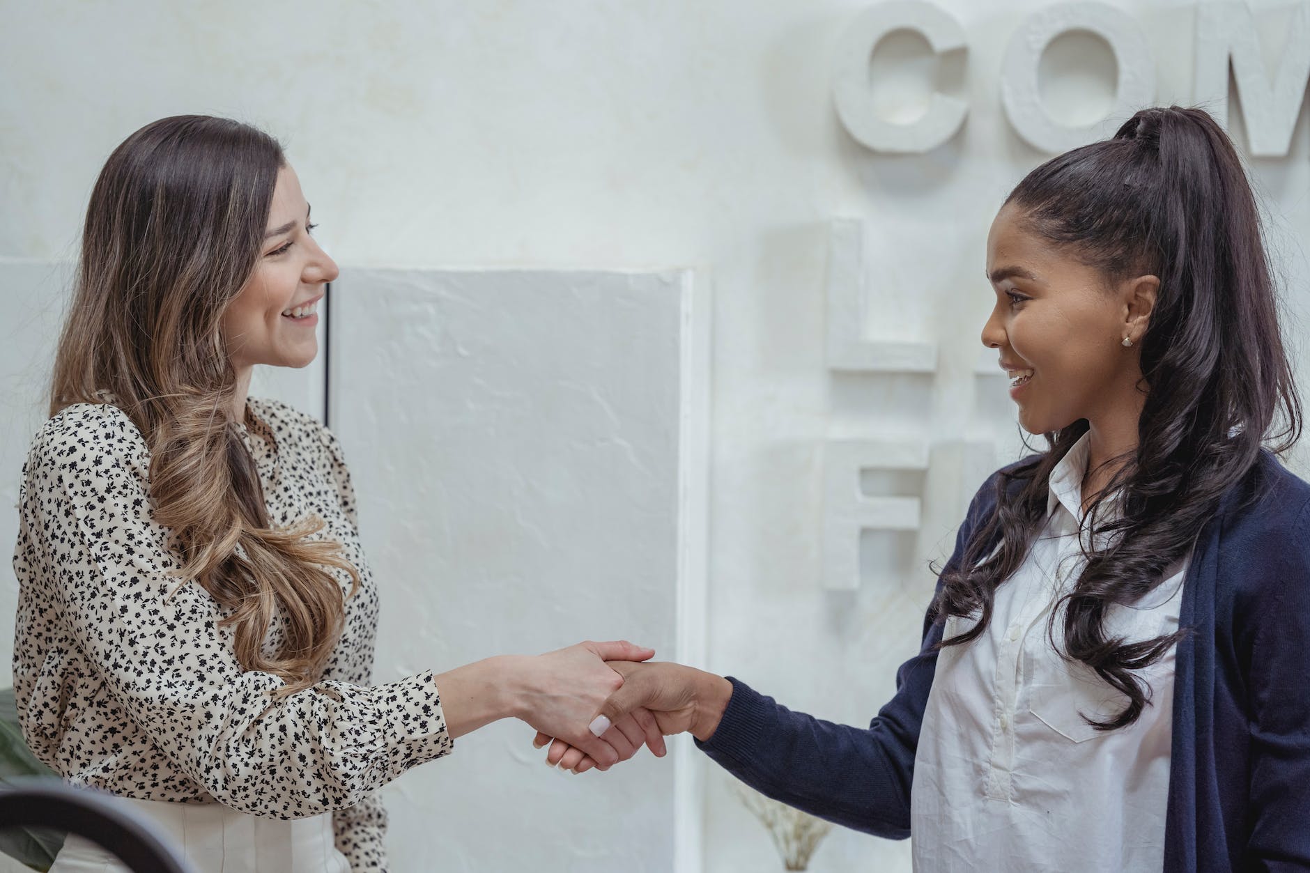 cheerful multiethnic businesswomen shaking hands in modern office