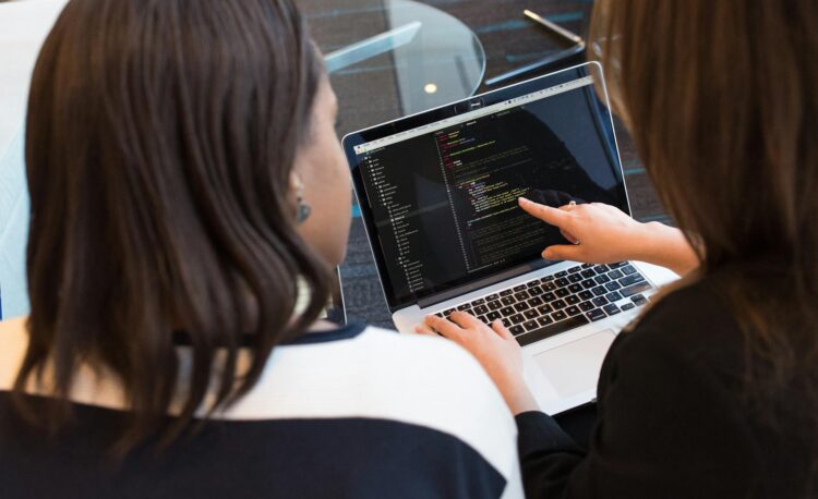 two women looking at the code at laptop