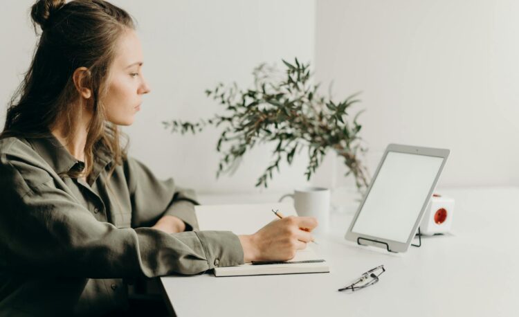 woman in gray coat using white laptop computer