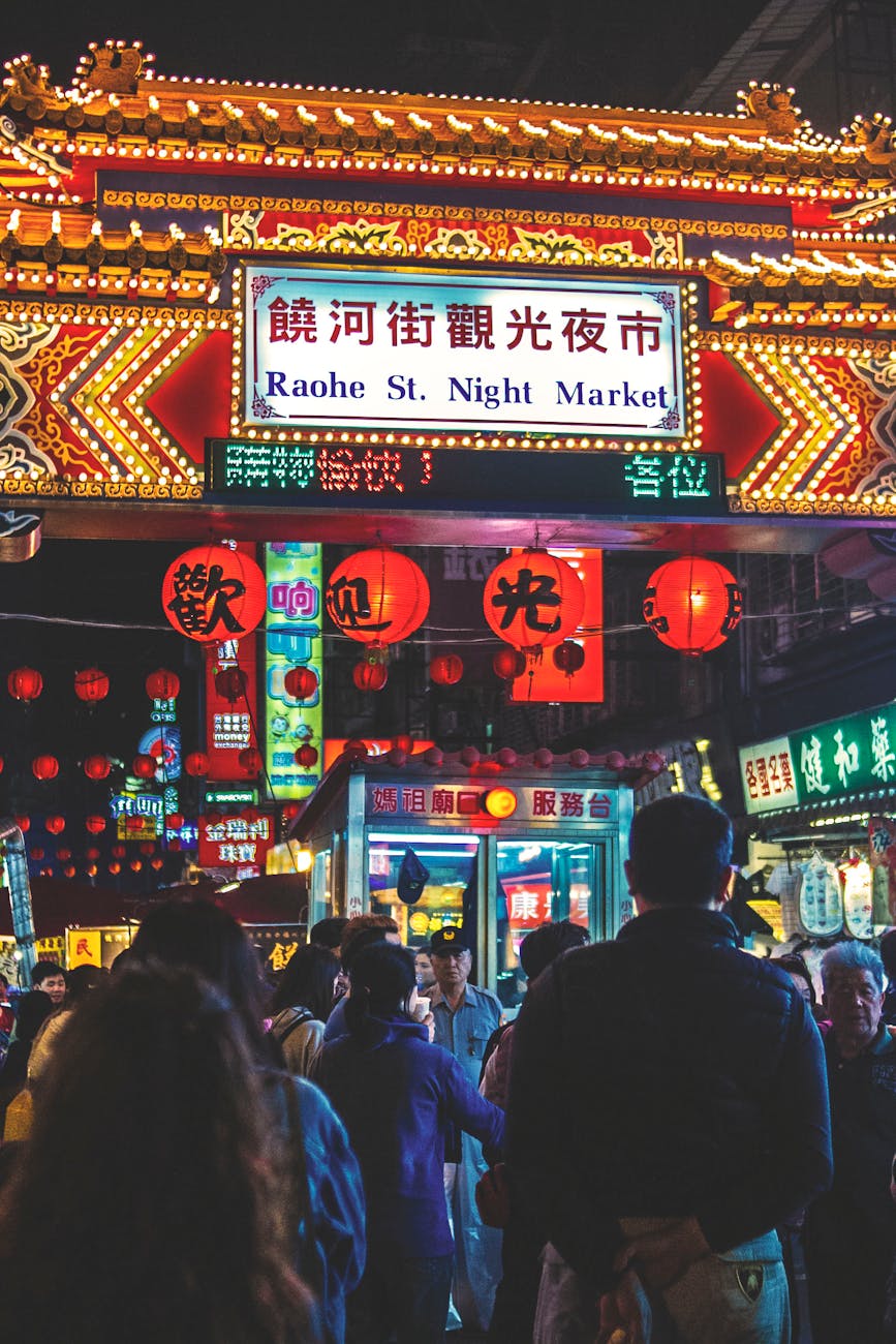 view of raohe st night market arch with kanji texts and group of people