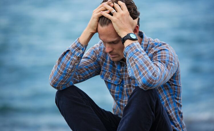 man in blue and brown plaid dress shirt touching his hair