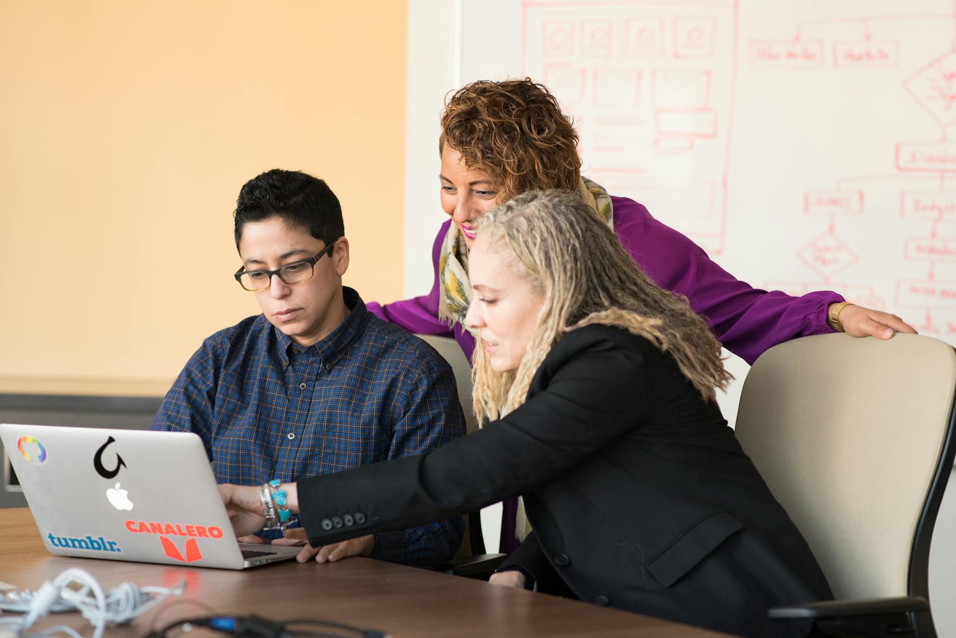 closeup photo of three person looking at macbook air