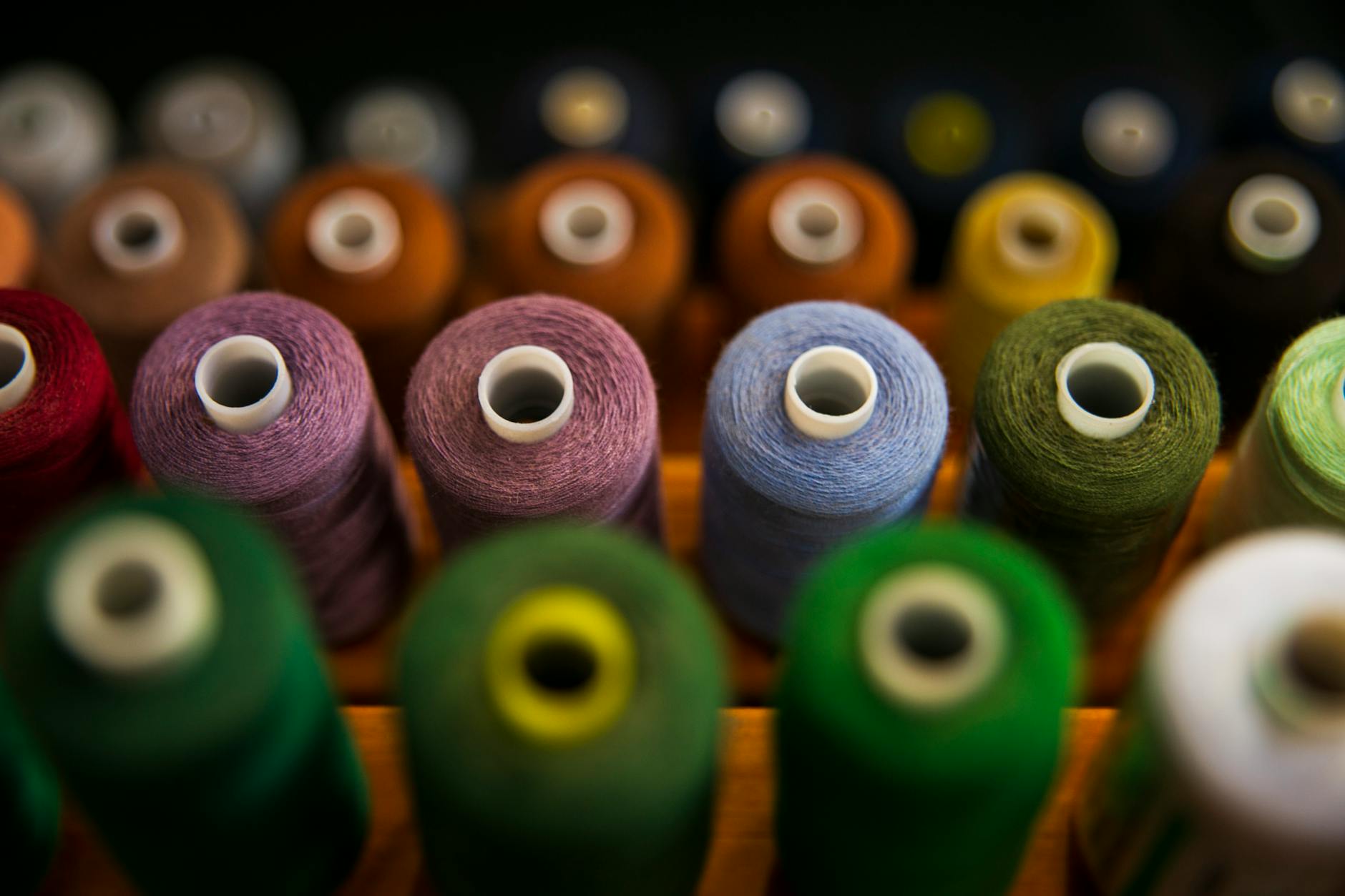 selective focus photography of assorted coloured thread spools