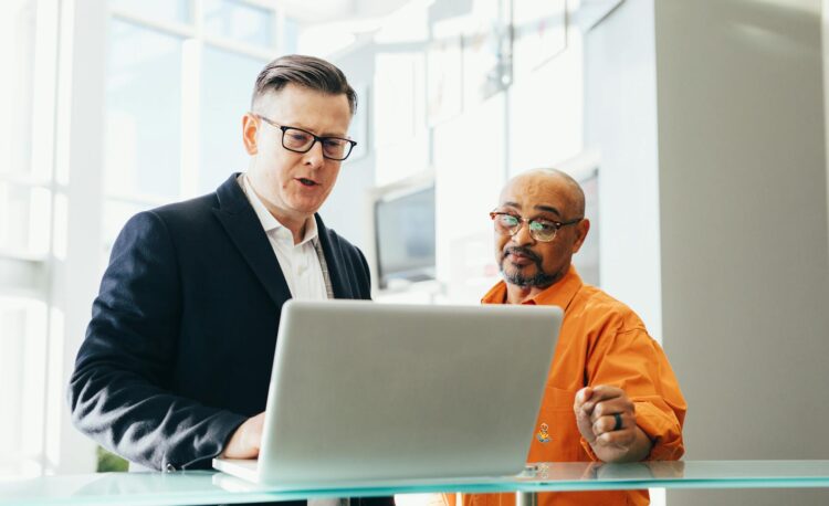 man using silver laptop beside another man