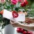 crop woman with valentine card near blooming flowers