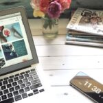 macbook air flower bouquet and magazines on white table